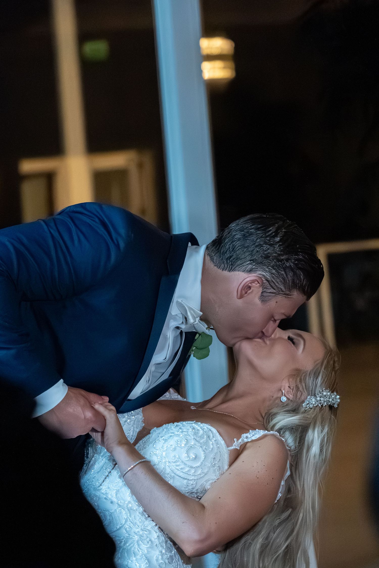 Bride and groom share a romantic dip kiss during their wedding reception dance.