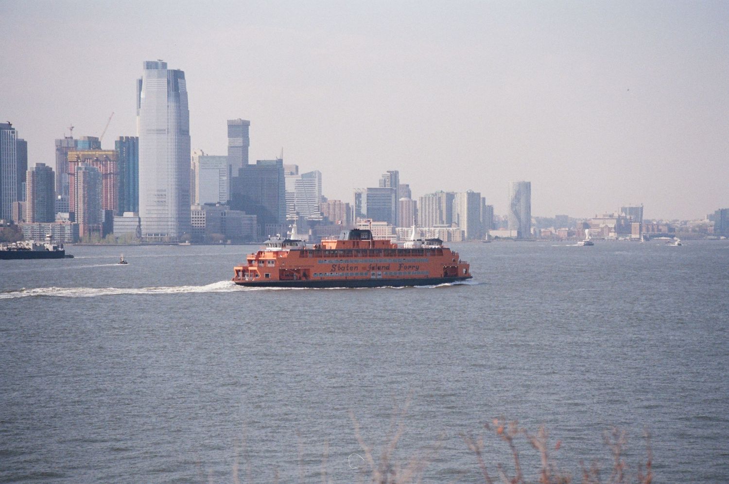 Staten Island Ferry crossing New York Harbor with the Manhattan skyline visible in the background.