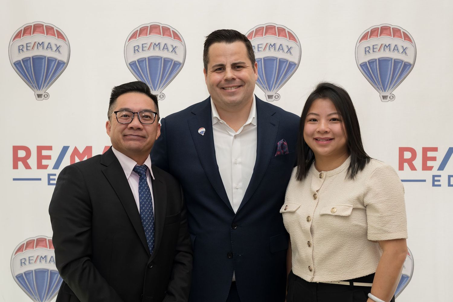 Three RE/MAX Edge real estate professionals pose together at company event.