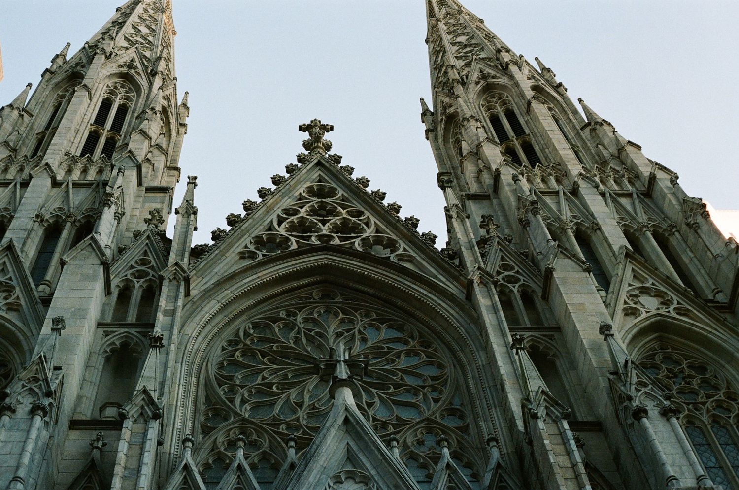Looking up at the stunning Gothic twin spires and ornate rose window facade of St. Patricks Cathedral in NYC.