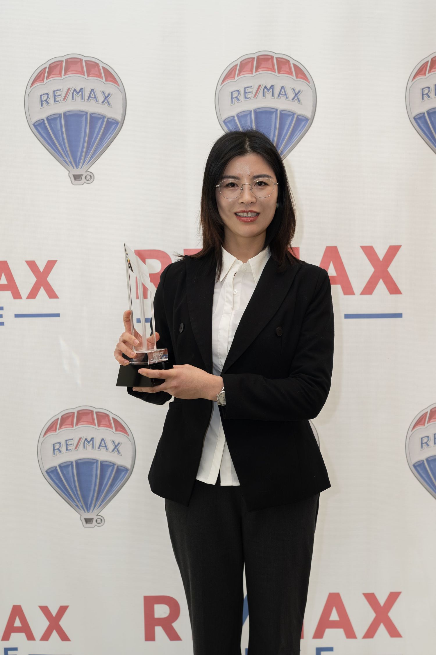 Female RE/MAX Edge agent proudly displays crystal award at RE/MAX ceremony.
