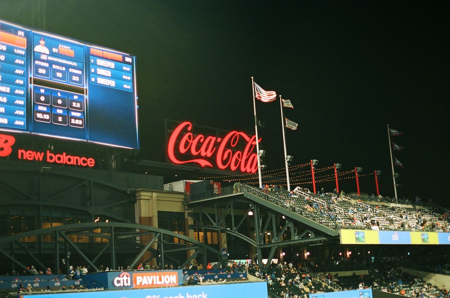 Coca-Cola sign and New Balance scoreboard lit up at Citi Field stadium at night.