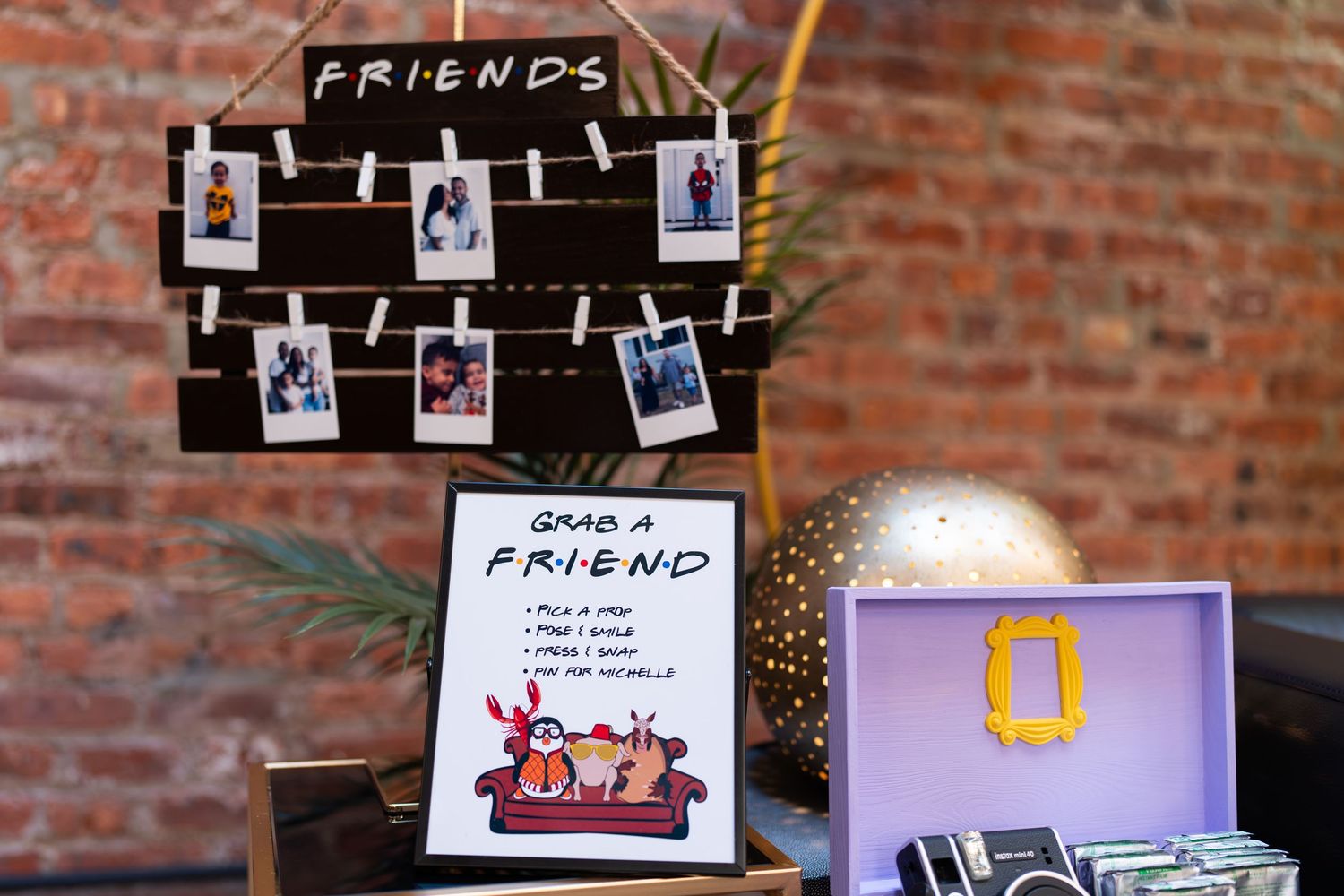 Friends TV show themed party display with Polaroid photos on clothesline and decorative signs.