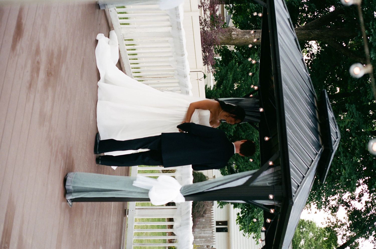 Bride and groom sharing romantic moment on steps surrounded by lush garden greenery.