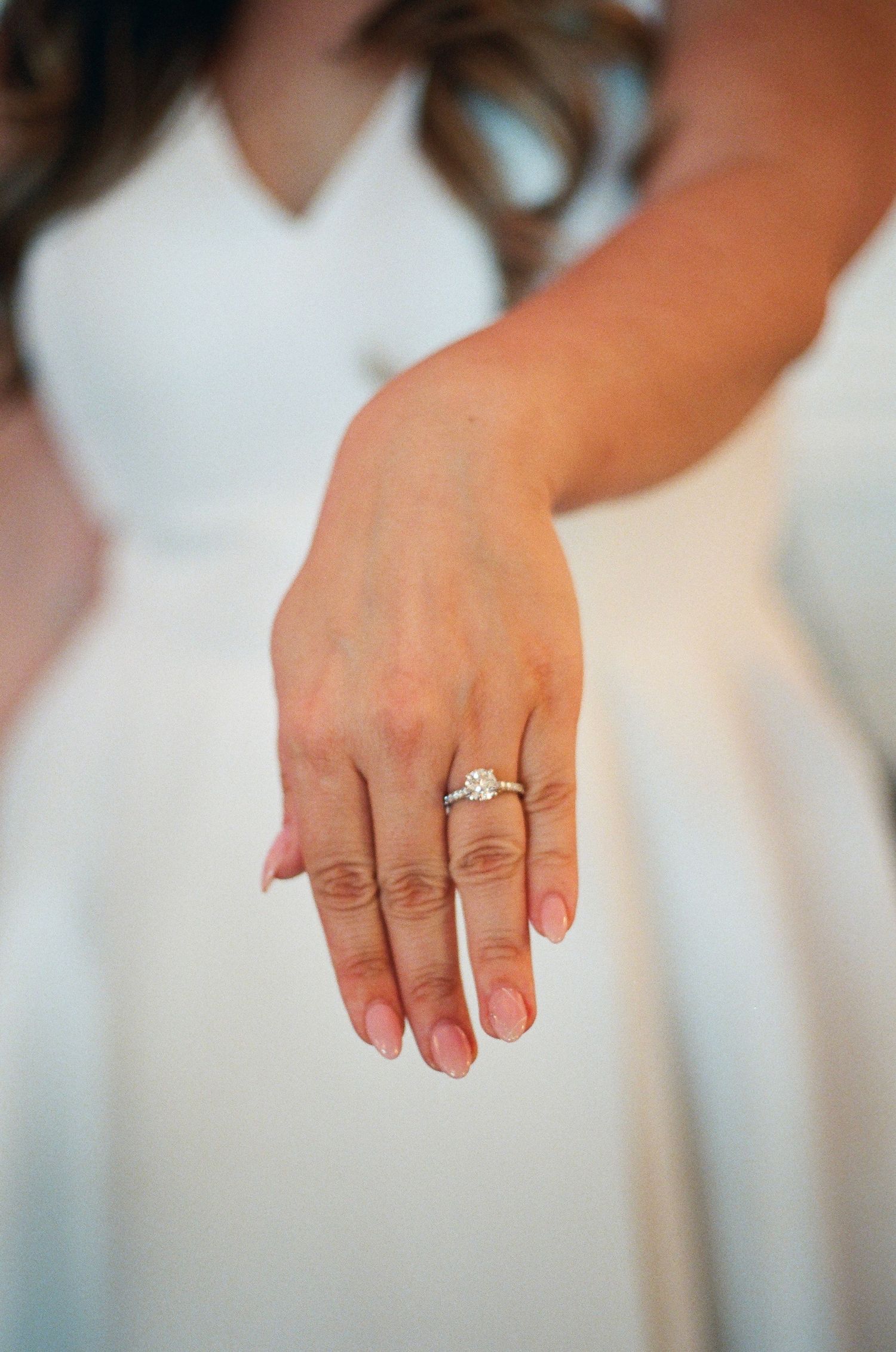 Close-up of bride showing diamond solitaire engagement ring on her wedding day.