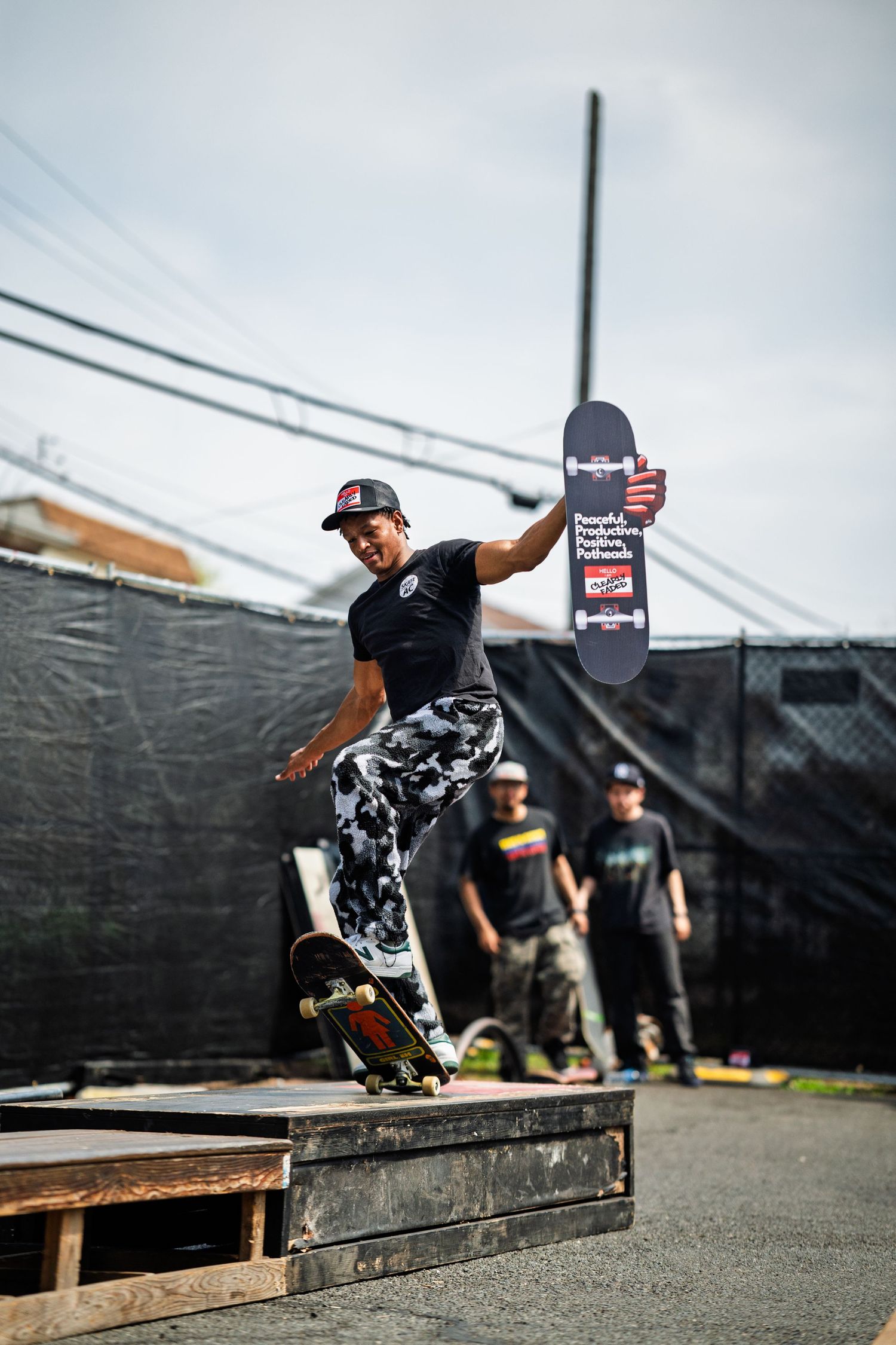 Skateboarder executing an impressive trick on a wooden platform at an outdoor skate competition.