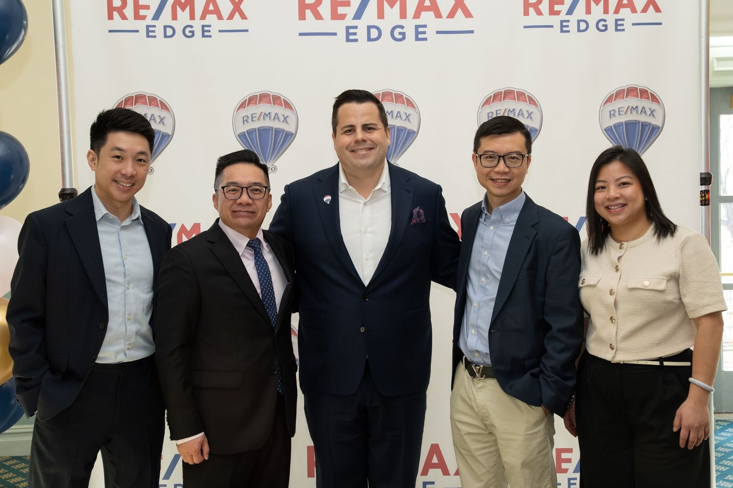 Group of five professionals pose at RE/MAX Edge real estate event.