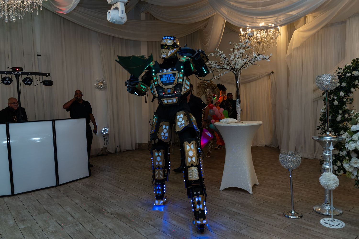 LED robot costume performer stands in elegantly decorated event venue with white draping.