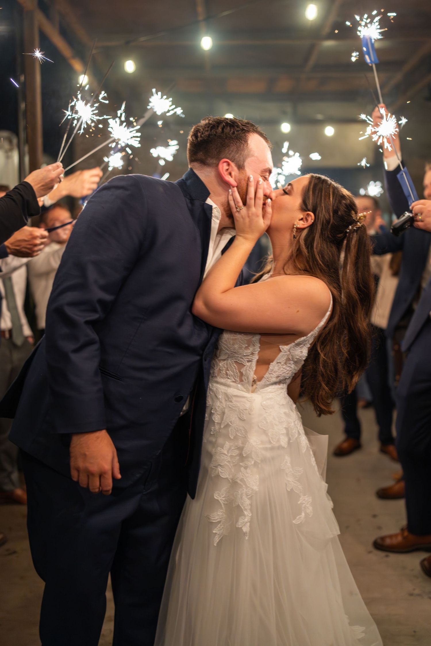 Newlyweds share a romantic kiss during sparkler send-off at their wedding reception.