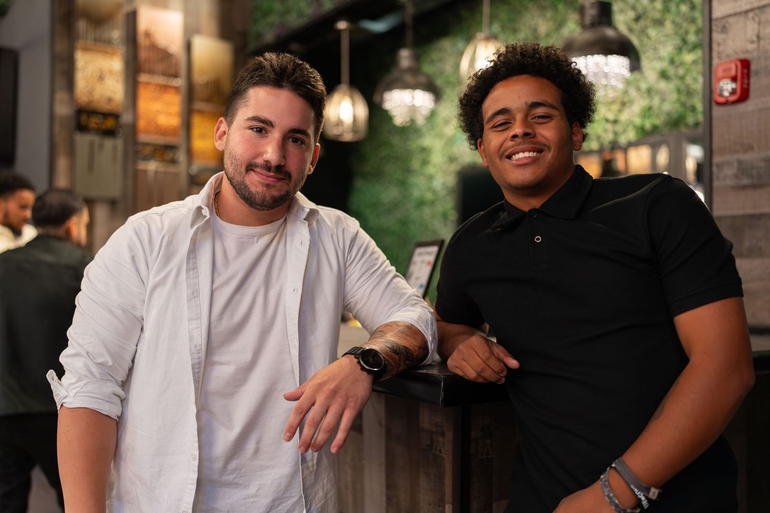 Two smiling men posing casually together at an indoor party venue.
