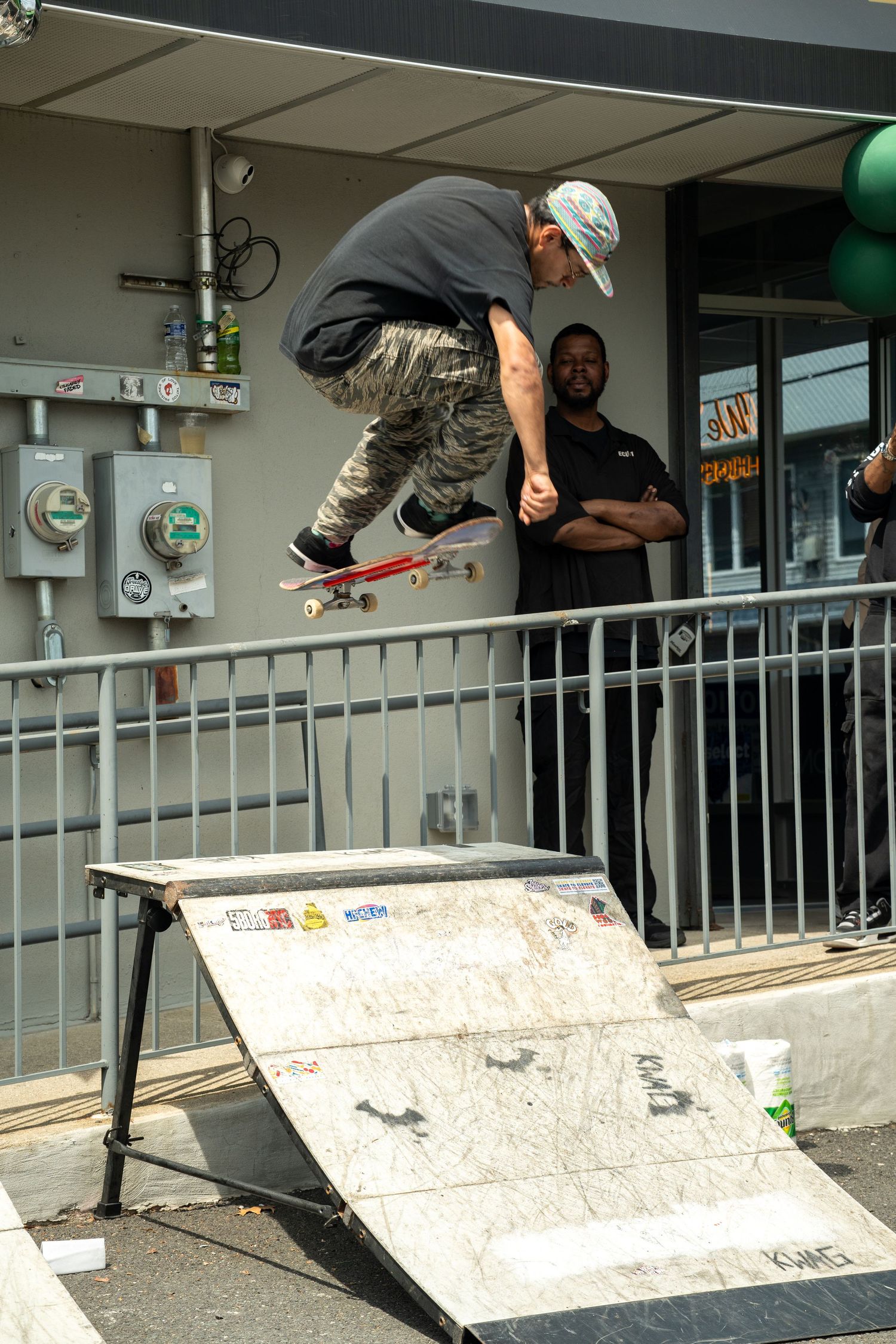 Skateboarder performing a jump trick on a ramp at an outdoor skate event.