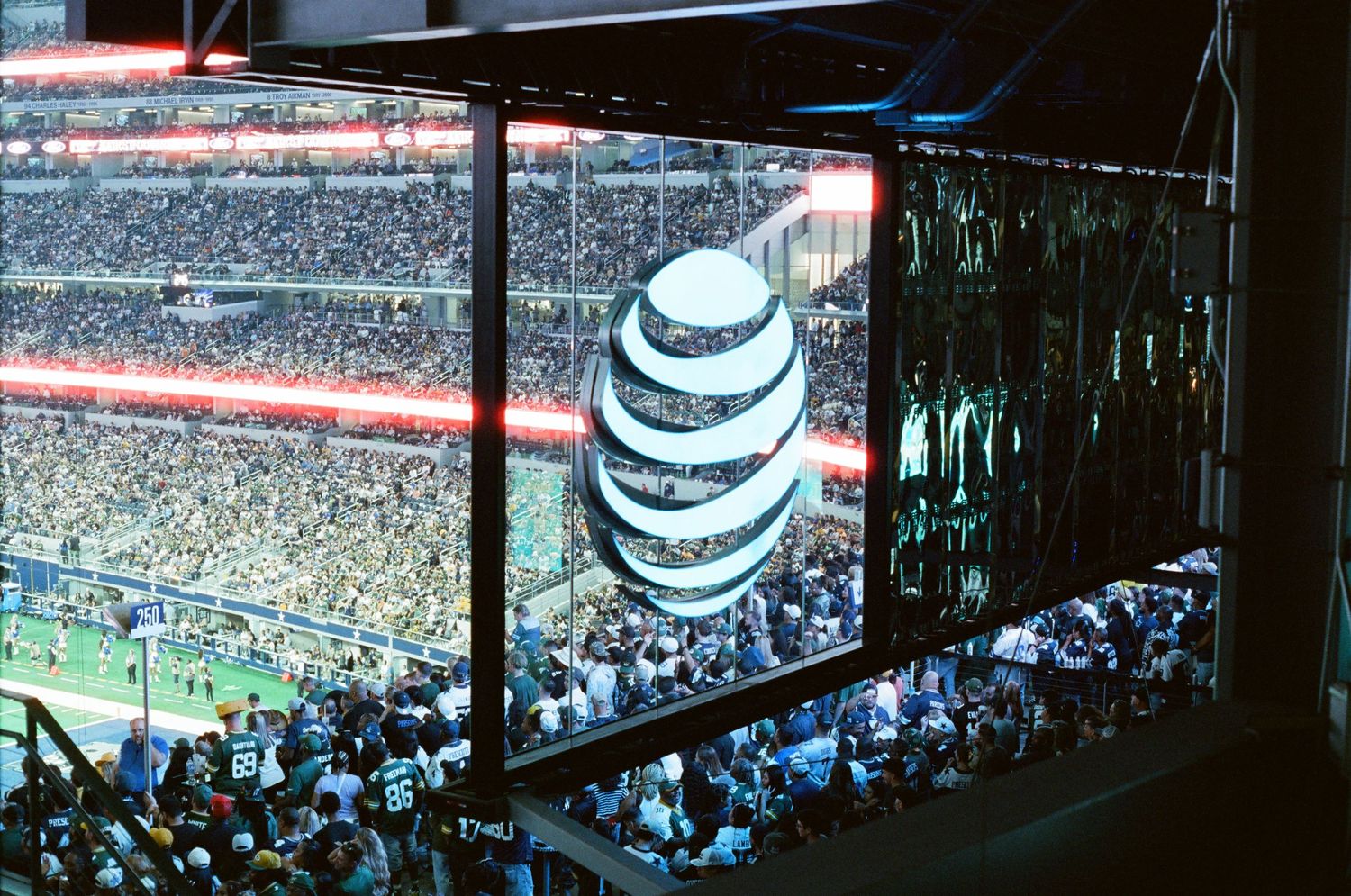AT&T logo displayed on large screen inside packed NFL stadium during a football game.