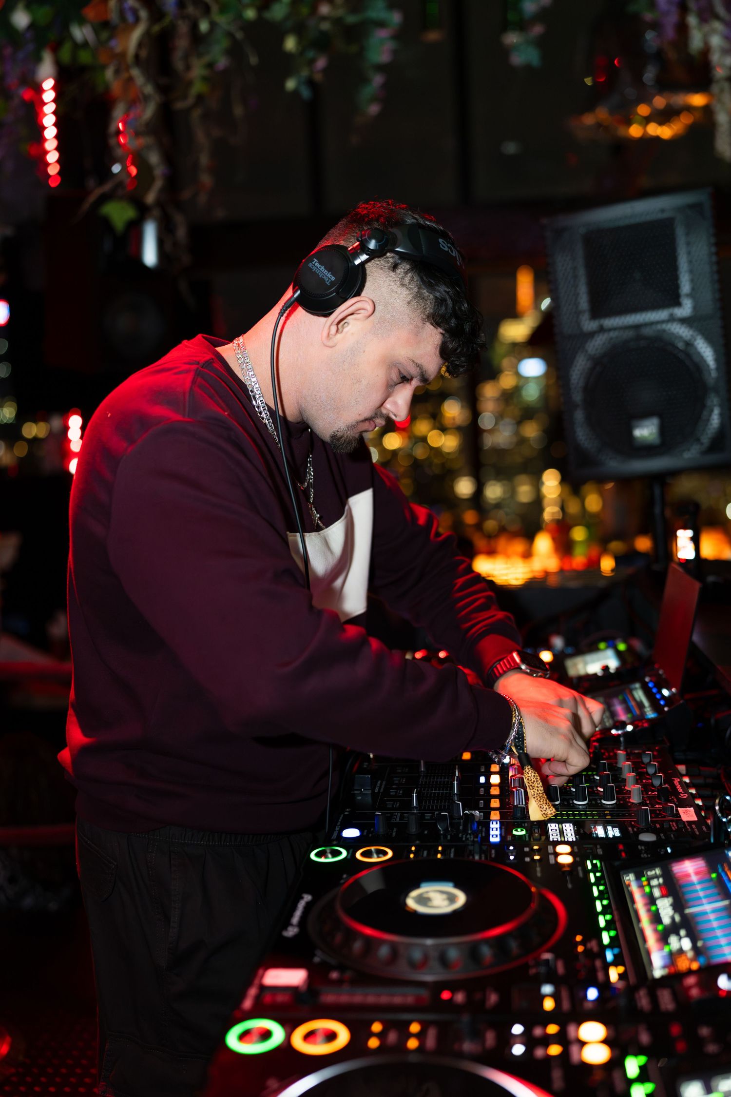 Male DJ with headphones mixing music on professional equipment at vibrant nightclub event.