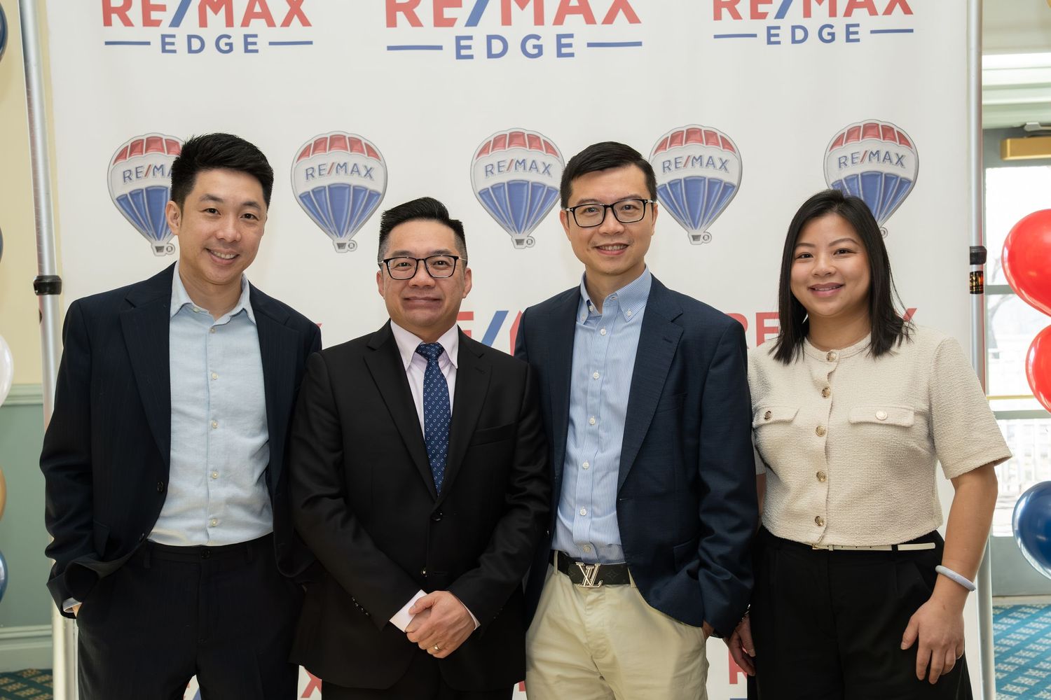 Four RE/MAX Edge real estate professionals smiling together in front of branded signage.