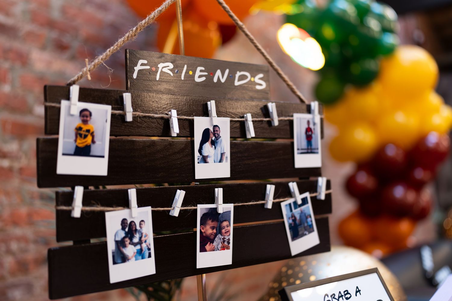 Rustic wooden Friends TV show photo display with Polaroid pictures clipped to string.