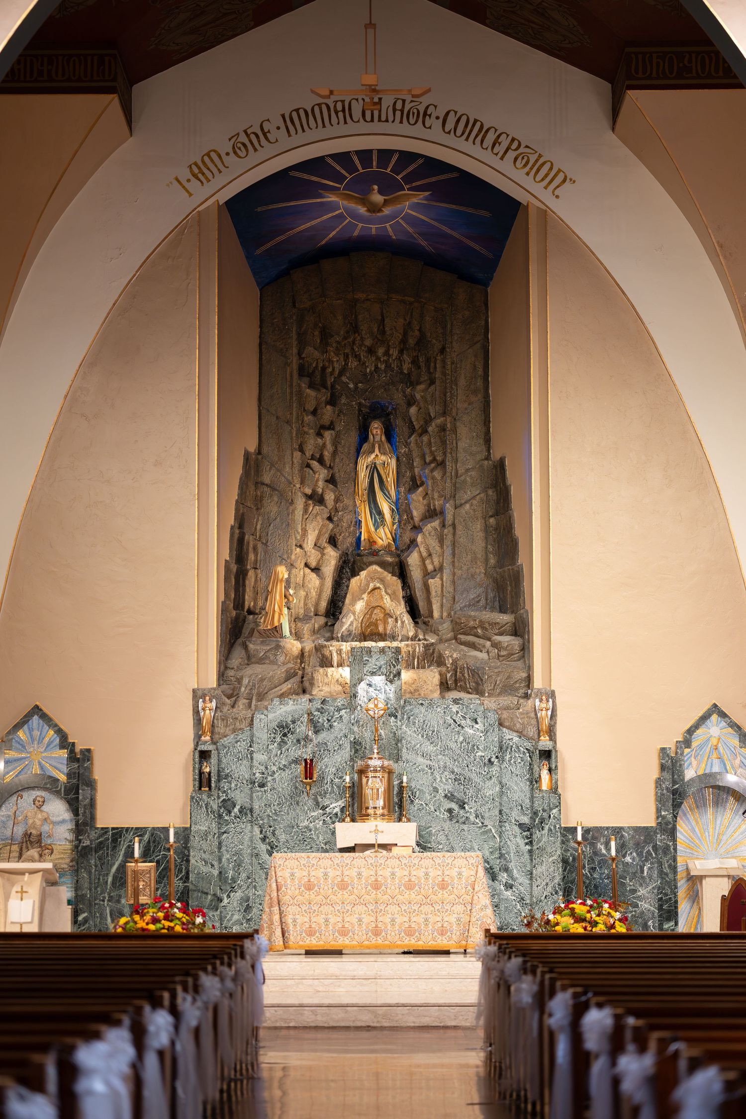 Interior of Immaculate Conception Church featuring ornate altar with statue and arched ceiling.
