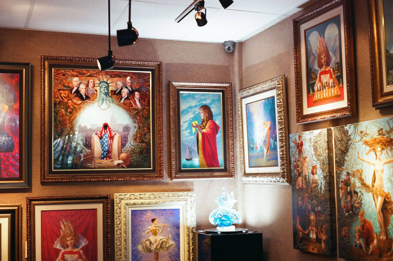 Ornate art gallery wall displaying vibrant fantasy and religious oil paintings in gilded gold frames.