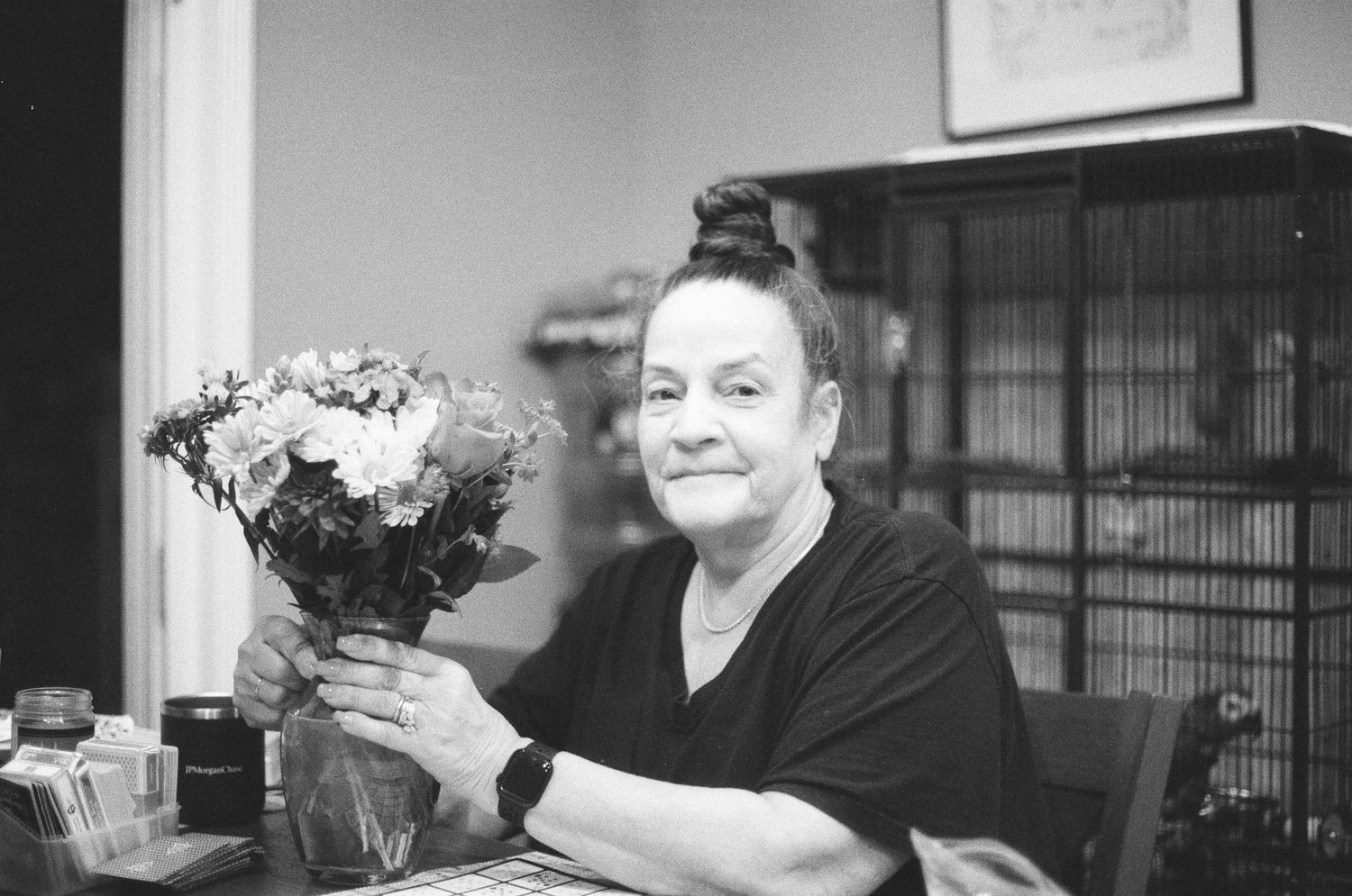 A woman holds a bouquet of flowers while sitting at a desk in a black and white portrait photo.