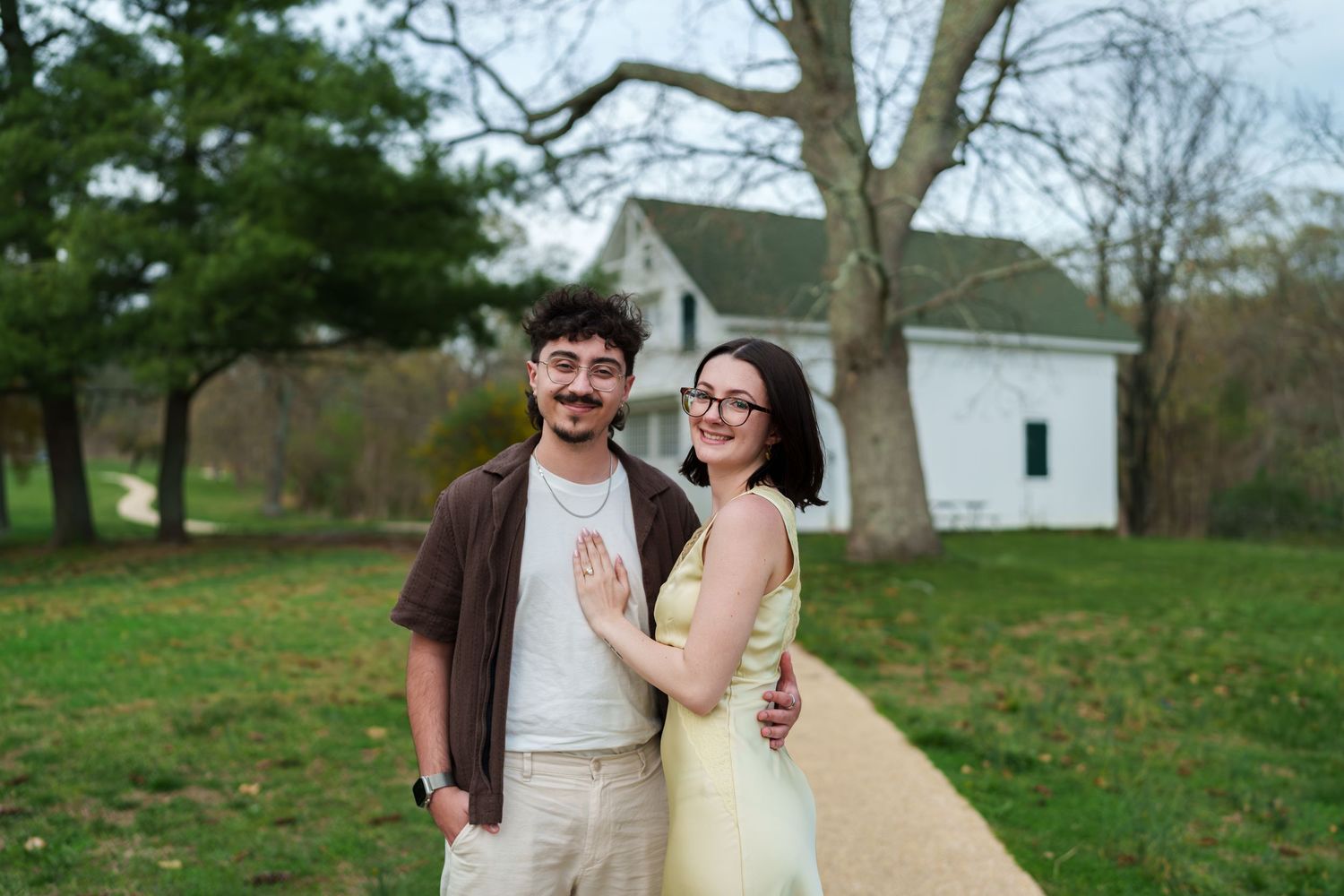 Joyful couple embracing on a scenic garden pathway near a charming white country building.