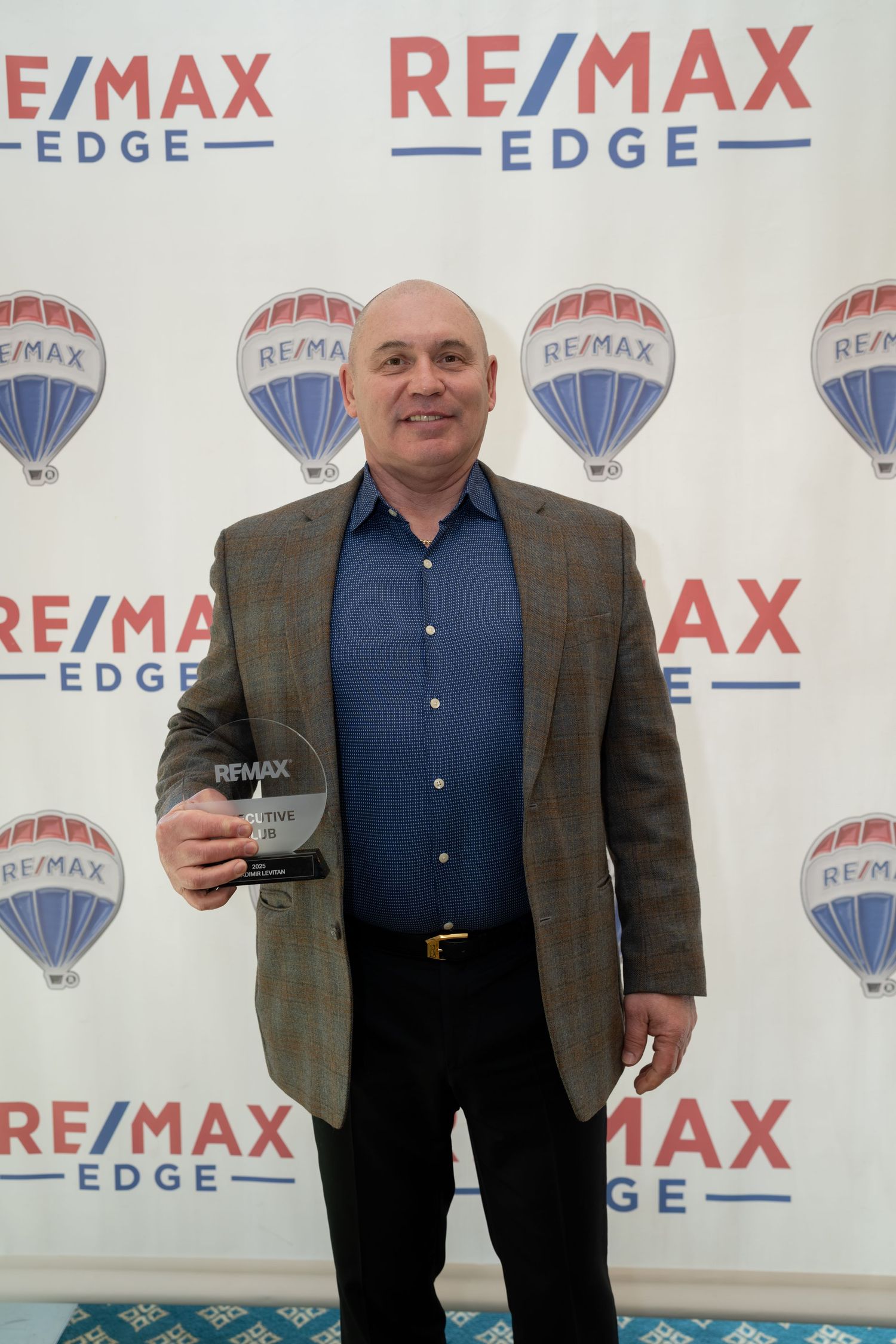 RE/MAX Edge award recipient proudly holds trophy at RE/MAX Edge recognition event.