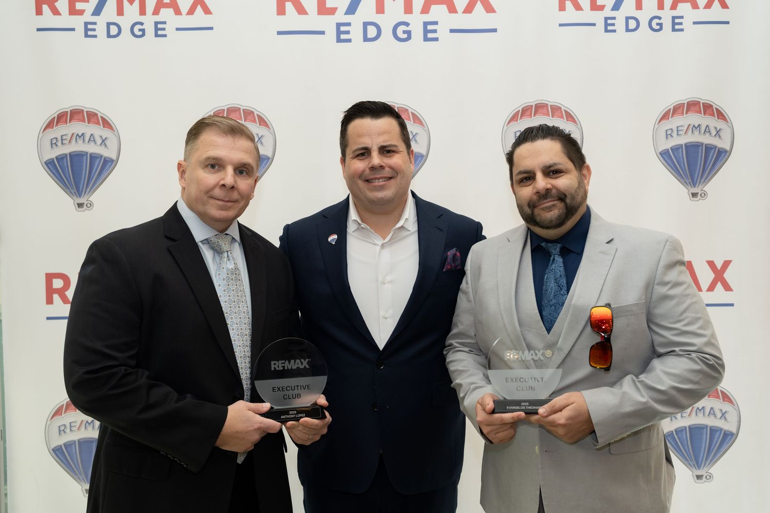 Three men hold RE/MAX awards at Edge real estate ceremony.