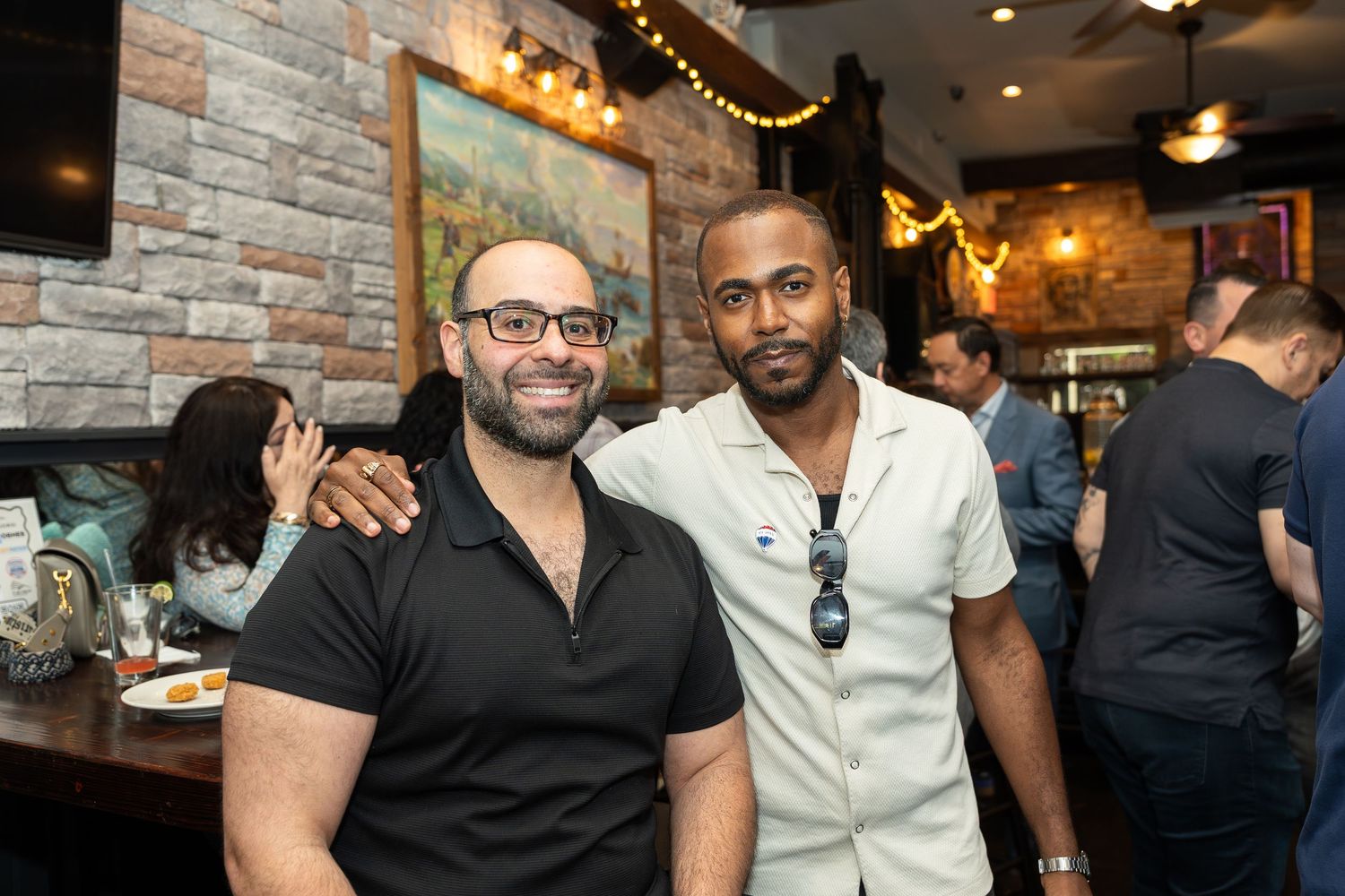 Two men smile together at a casual restaurant social gathering event.
