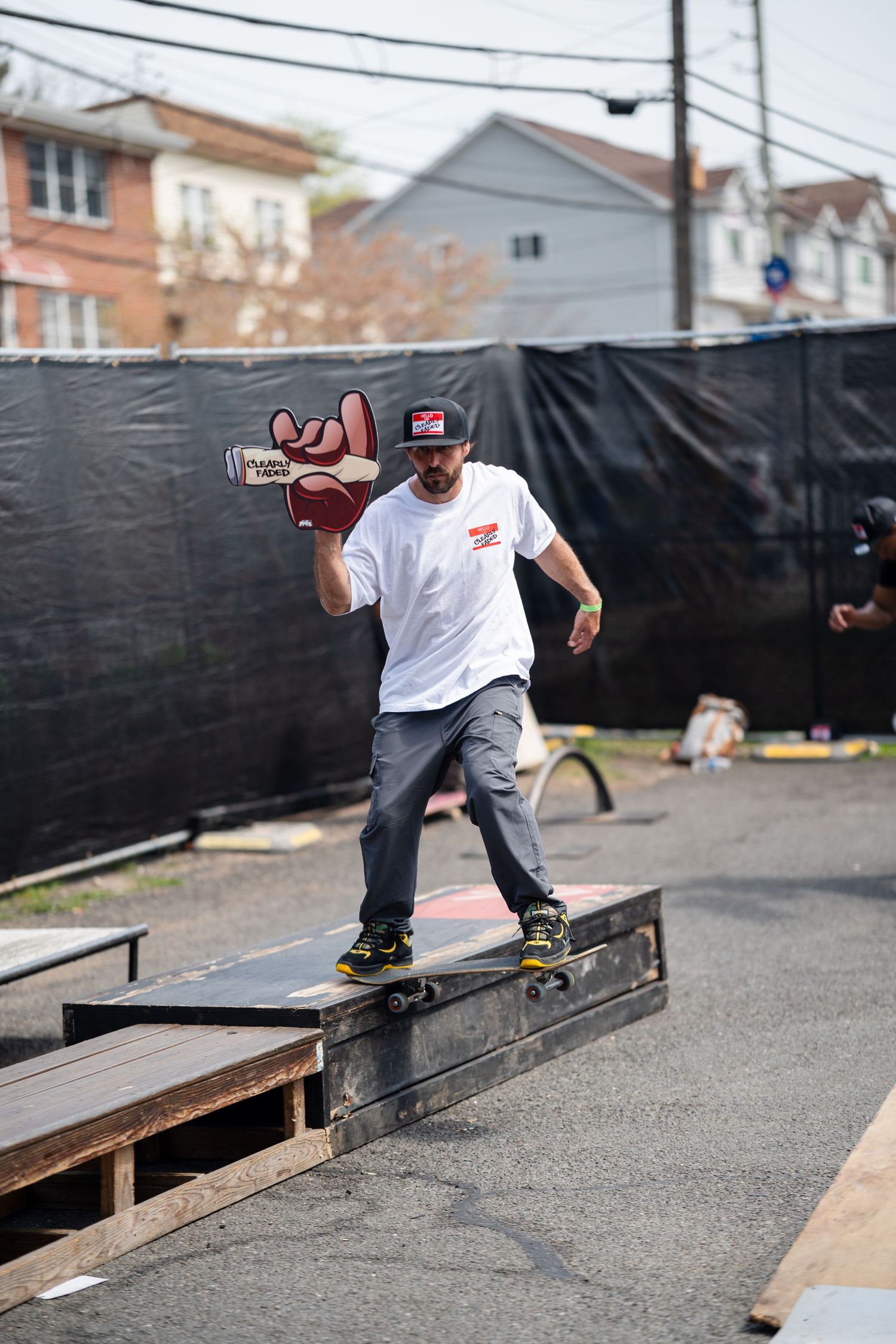 Skateboarder performing a grind trick on a wooden rail at an outdoor skate event.