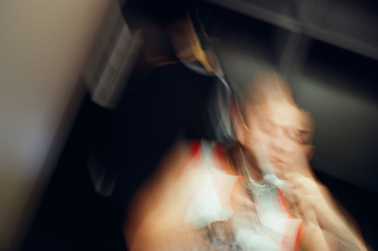 Blurred motion photograph of a wedding guest dancing at a reception in colorful attire.