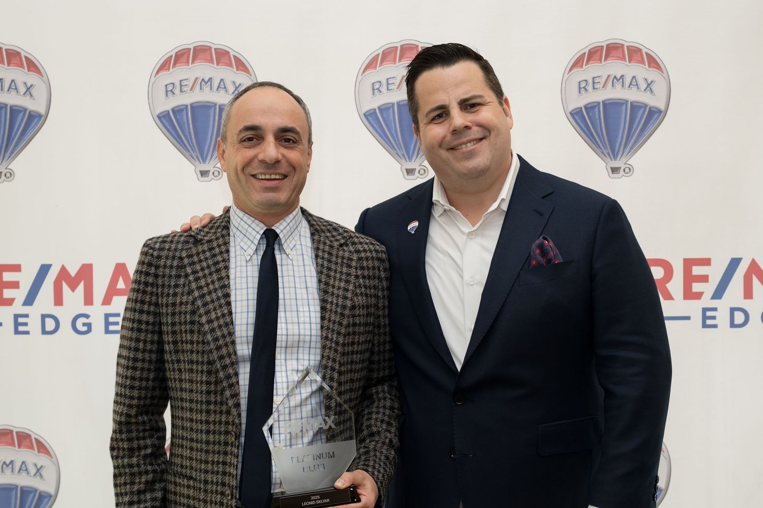 Two RE/MAX Edge male realtors pose with achievement award at RE/MAX ceremony.