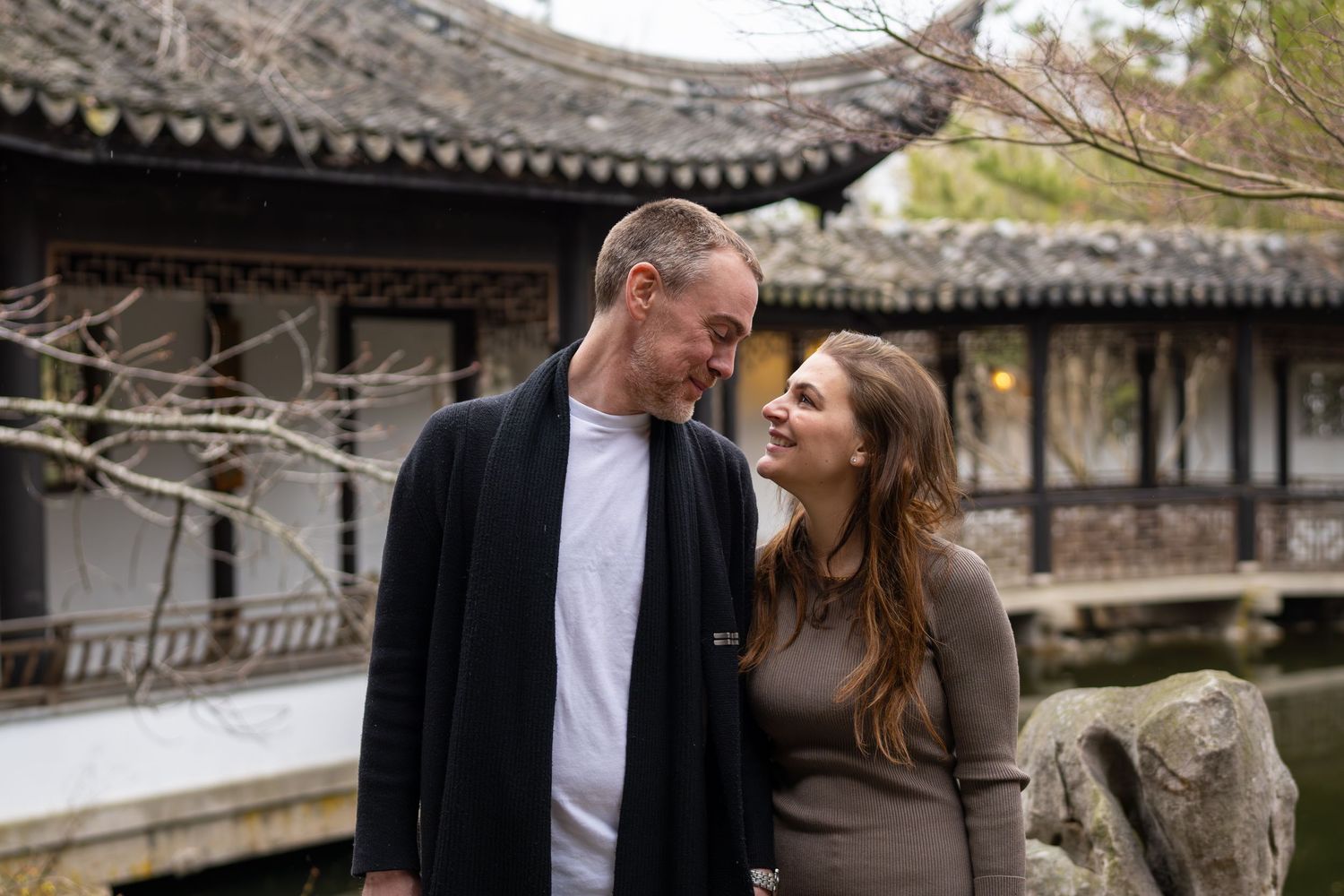 Happy couple gazing at each other lovingly in a serene Chinese garden setting.