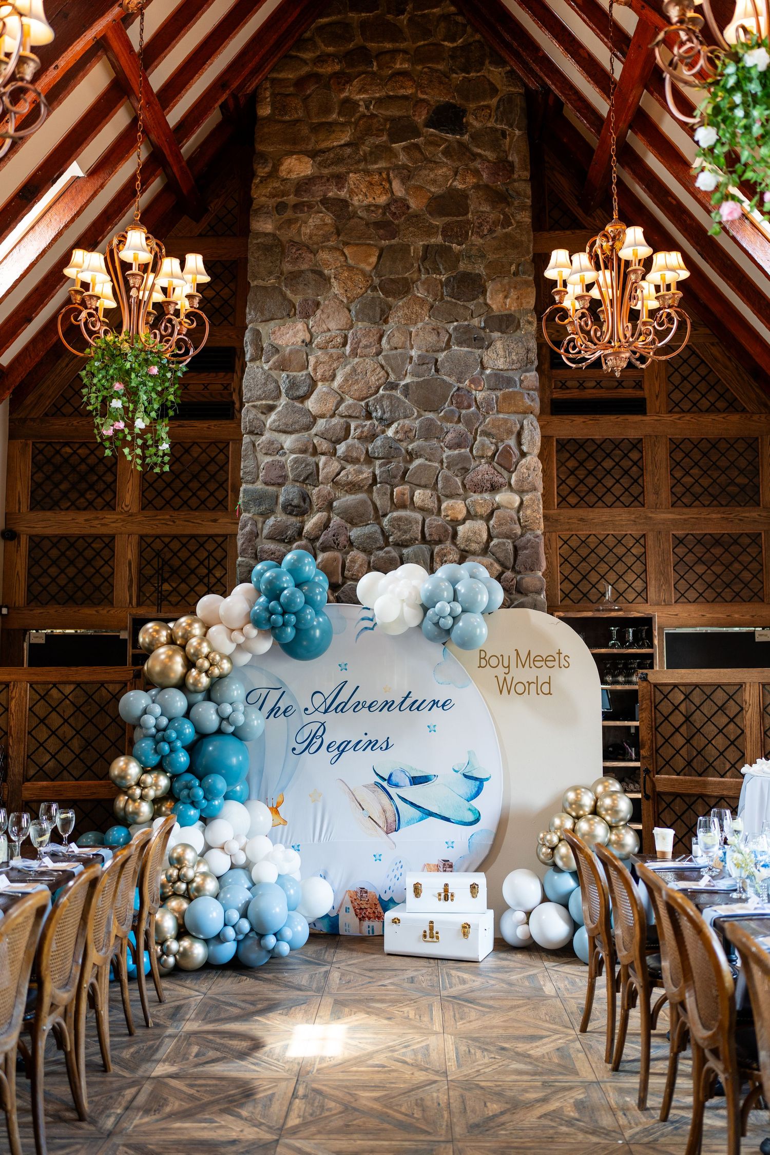 Elegant baby shower venue with blue balloon arch and Boy Meets World adventure theme decor.