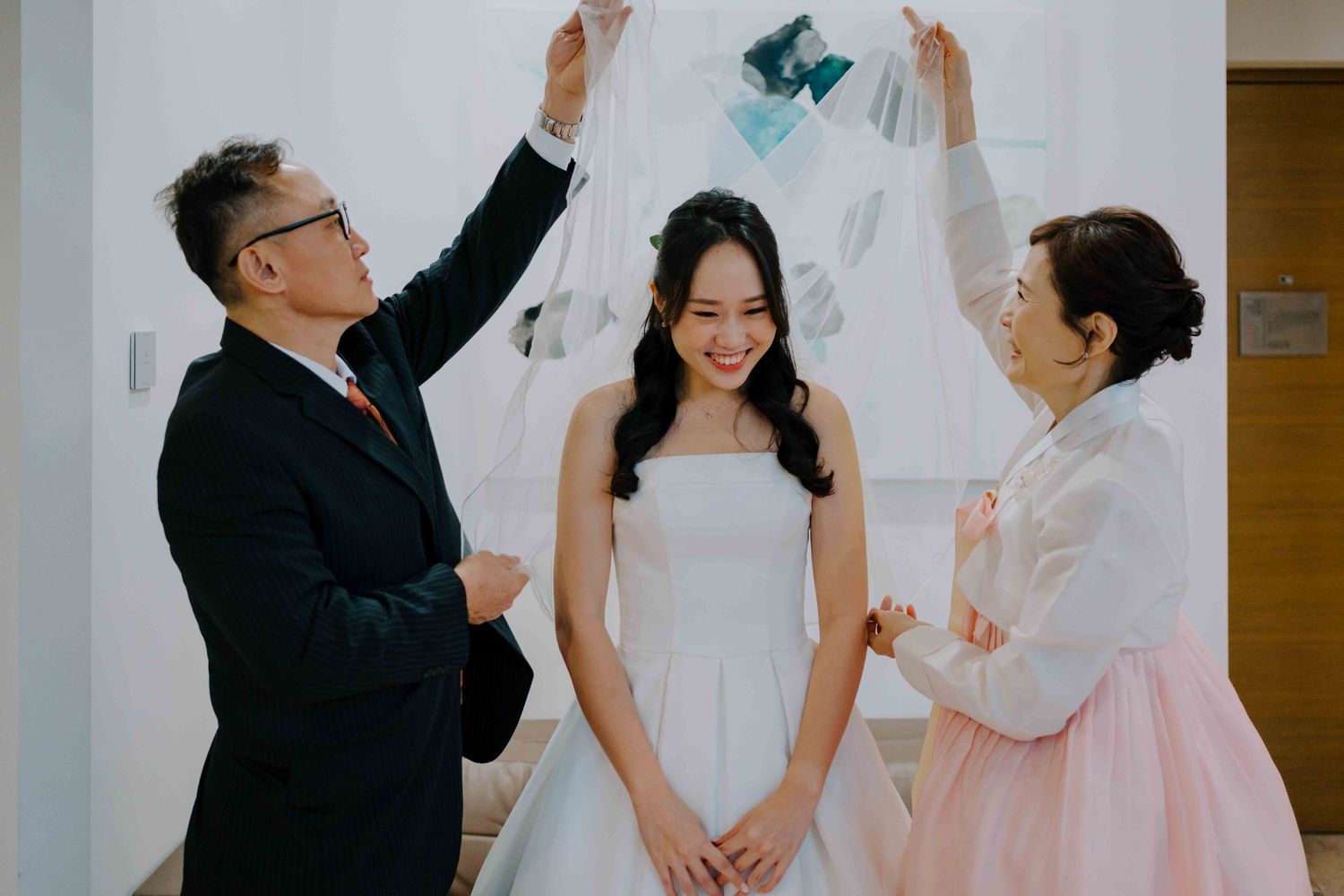 bride's parents help bride wear her veil on wedding day at one farrer hotel singapore