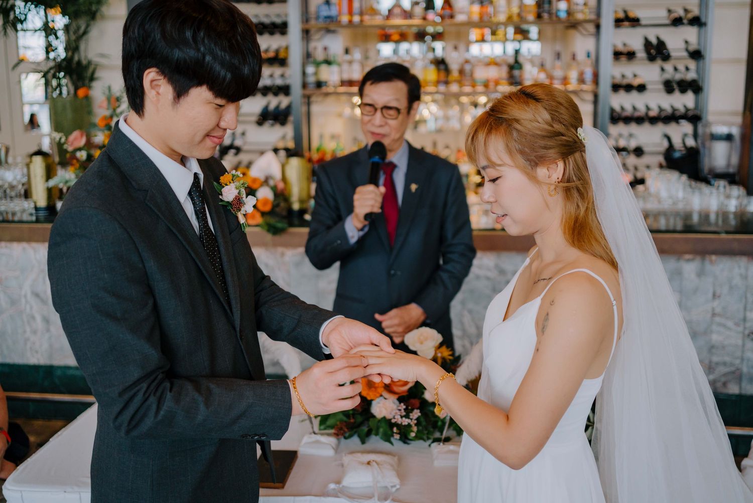 groom fits wedding ring into bride's ring finger