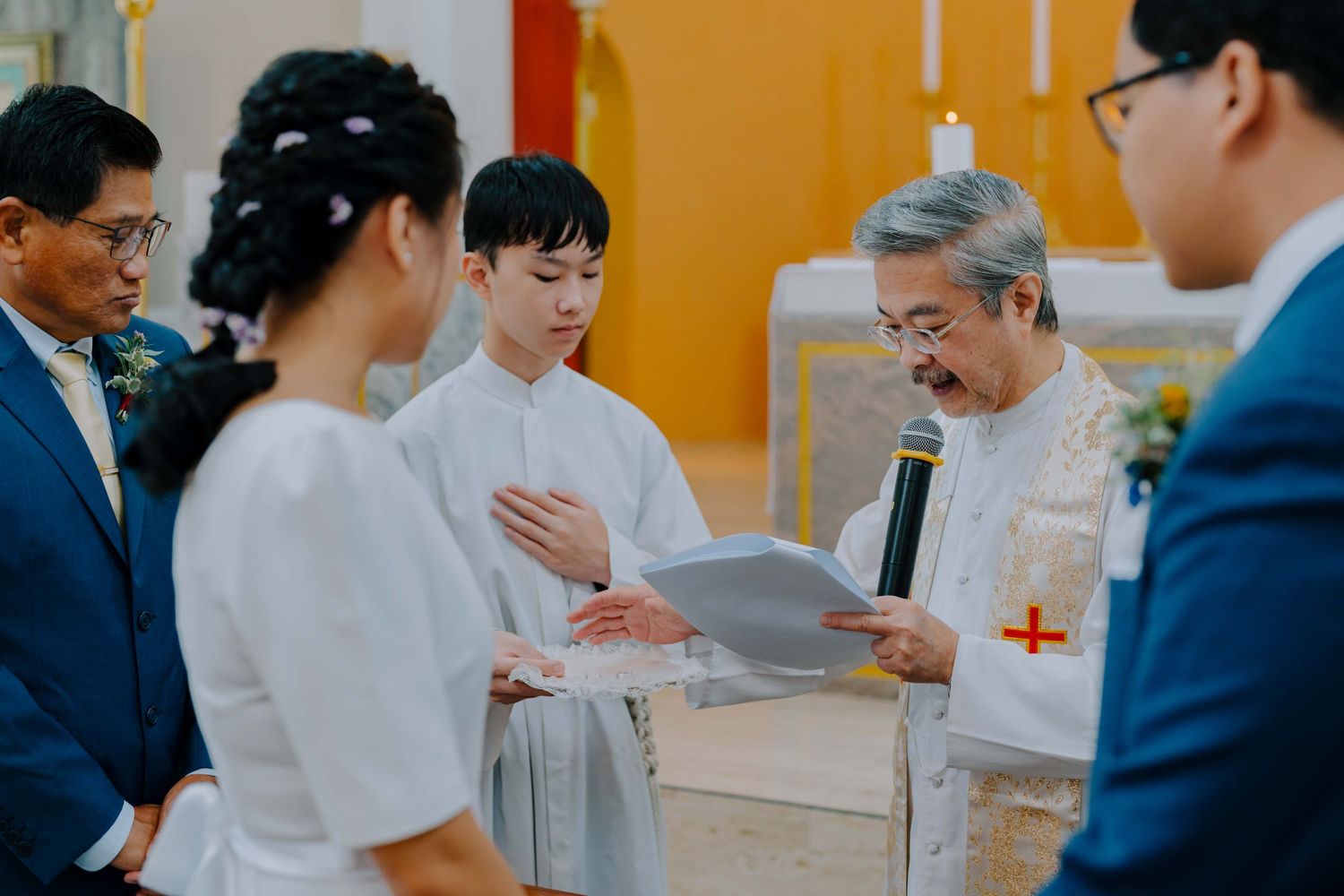 catholic church father blesses wedding ring bands for the newlywed couple