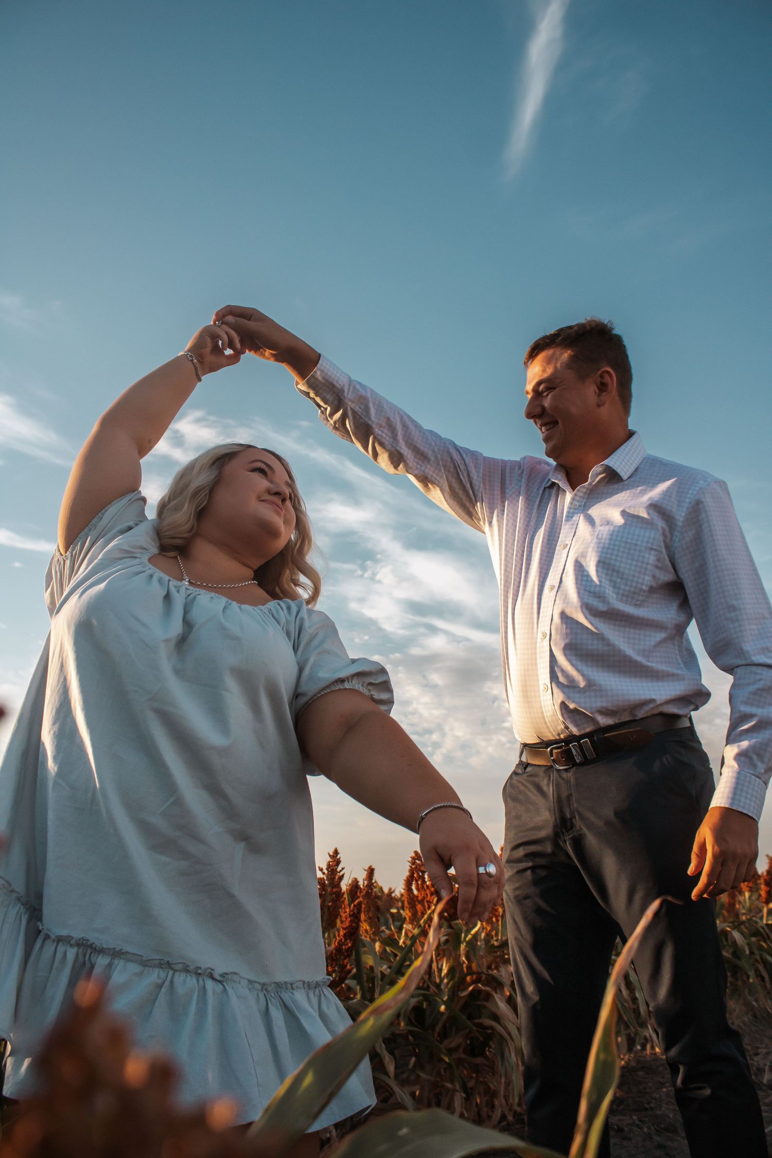 A couple dances together in a corn field at sunset with dramatic lighting and movement.
