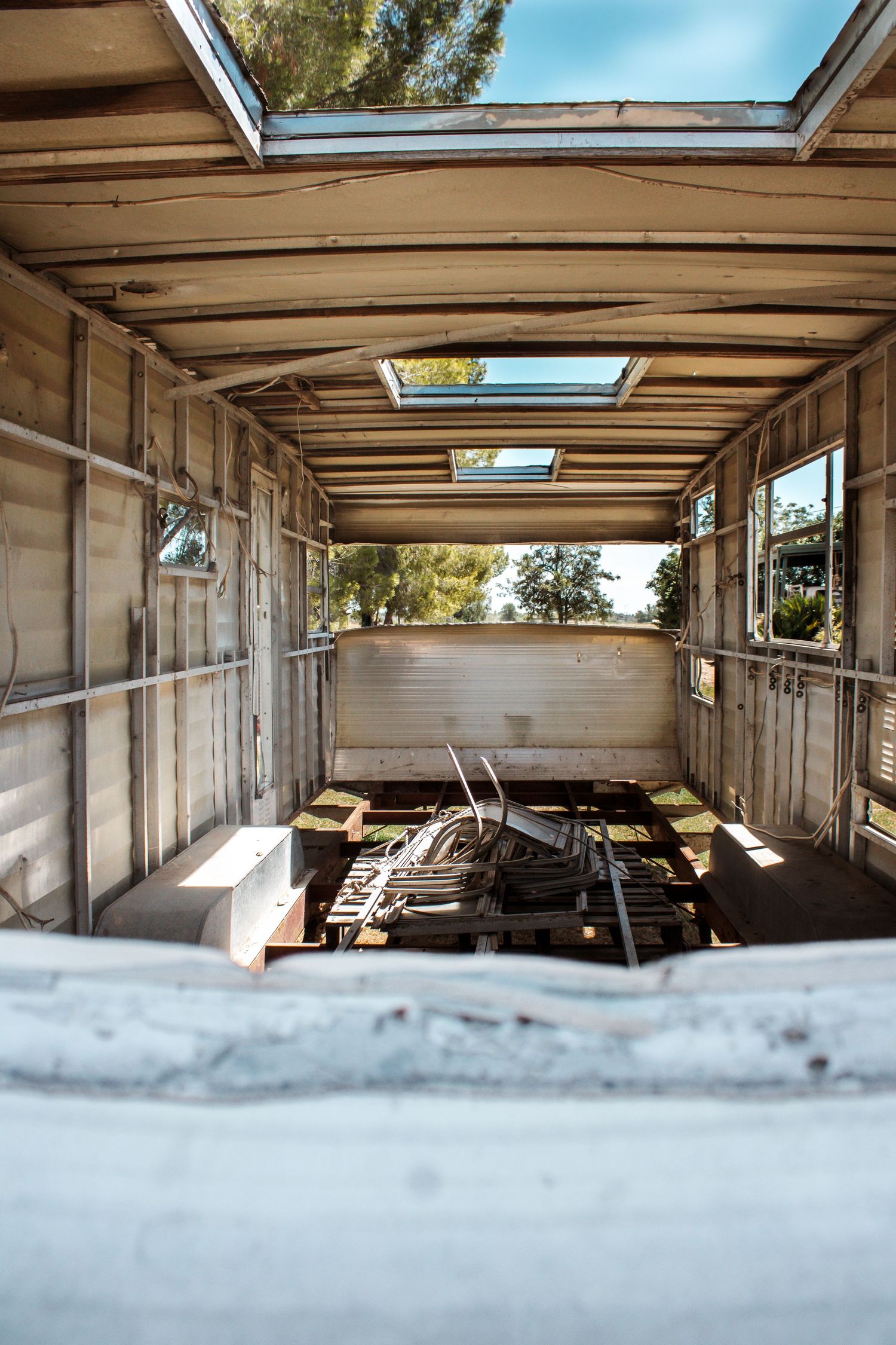 Interior view of an abandoned trailer with skylights showing natural light streaming in through the roof panels.