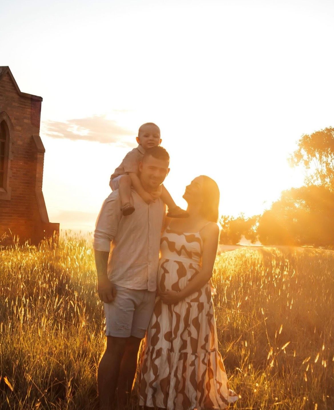 A couple embraces in a golden wheat field at sunset creating a romantic silhouette against the warm glowing sky.