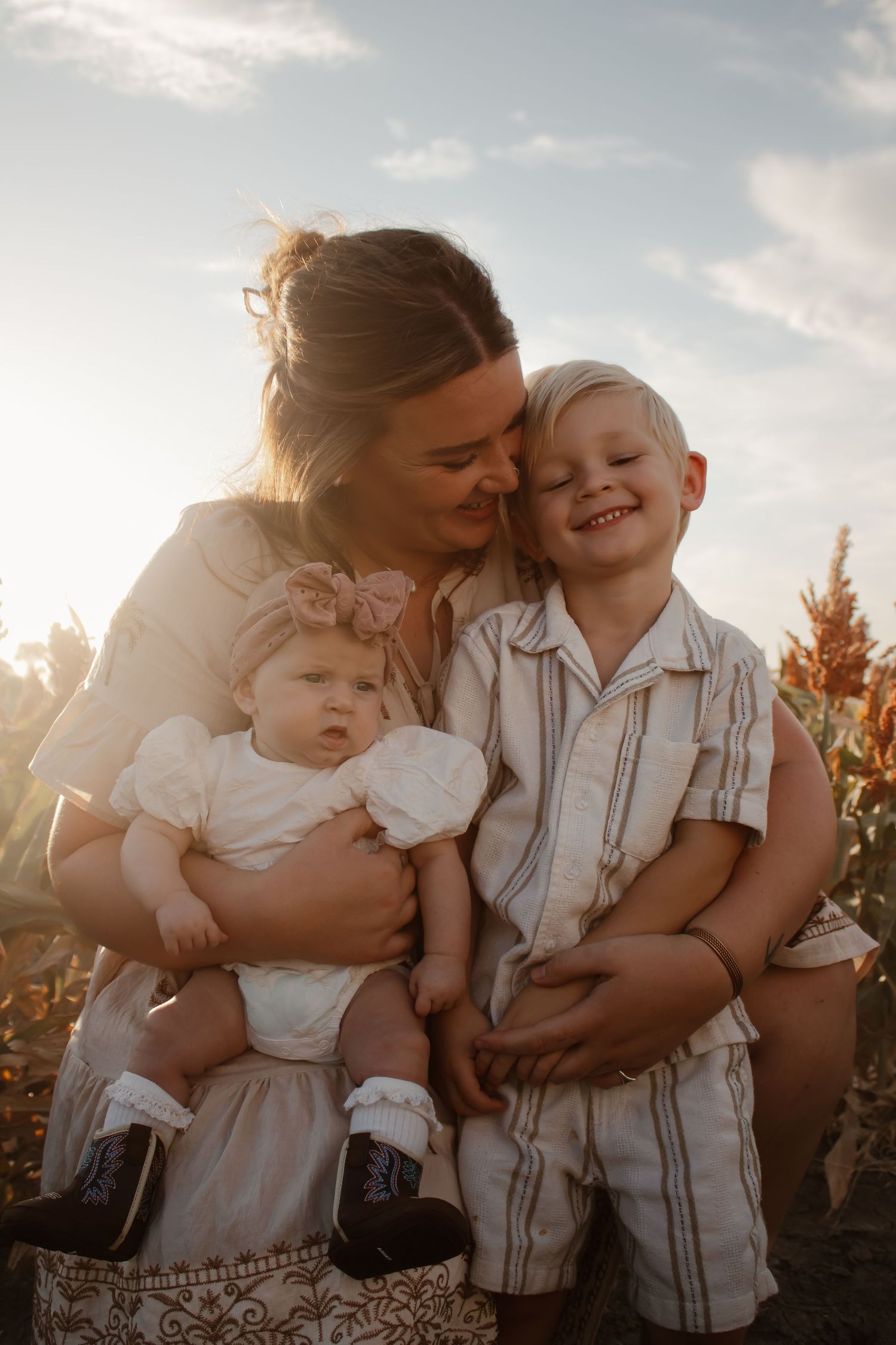 A loving family embraces and shares tender moments together at sunset in a golden-lit outdoor setting.