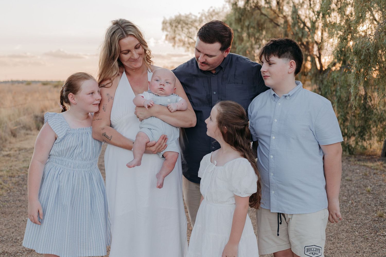 A family in coordinating blue and white outfits shares joyful moments together during an outdoor photo session.