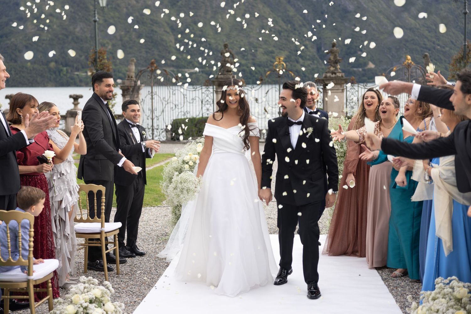 Wedding celebration with falling confetti and guests gathered outside a historic building.