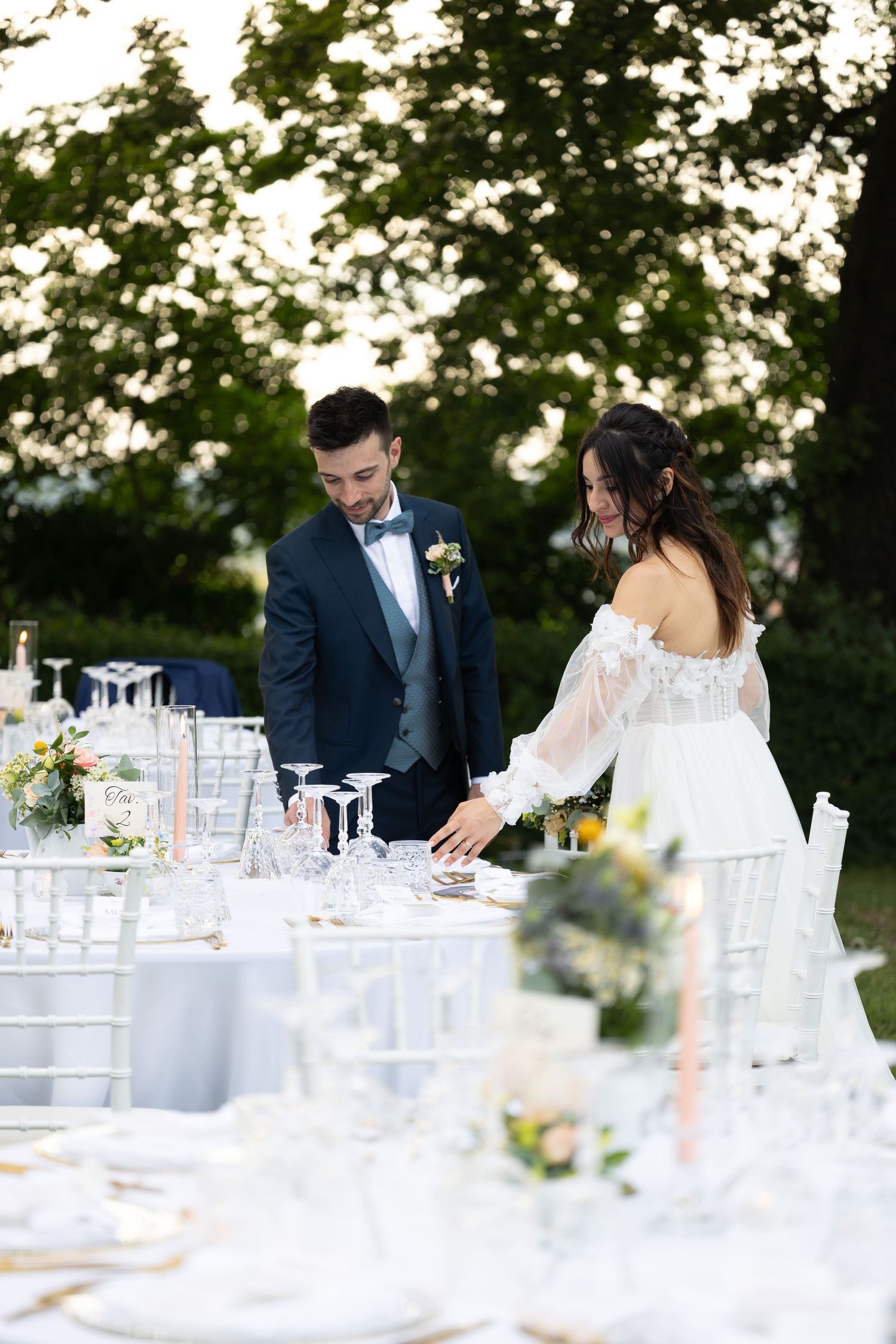 Elegant outdoor wedding reception setup with white chairs and floral table decorations.