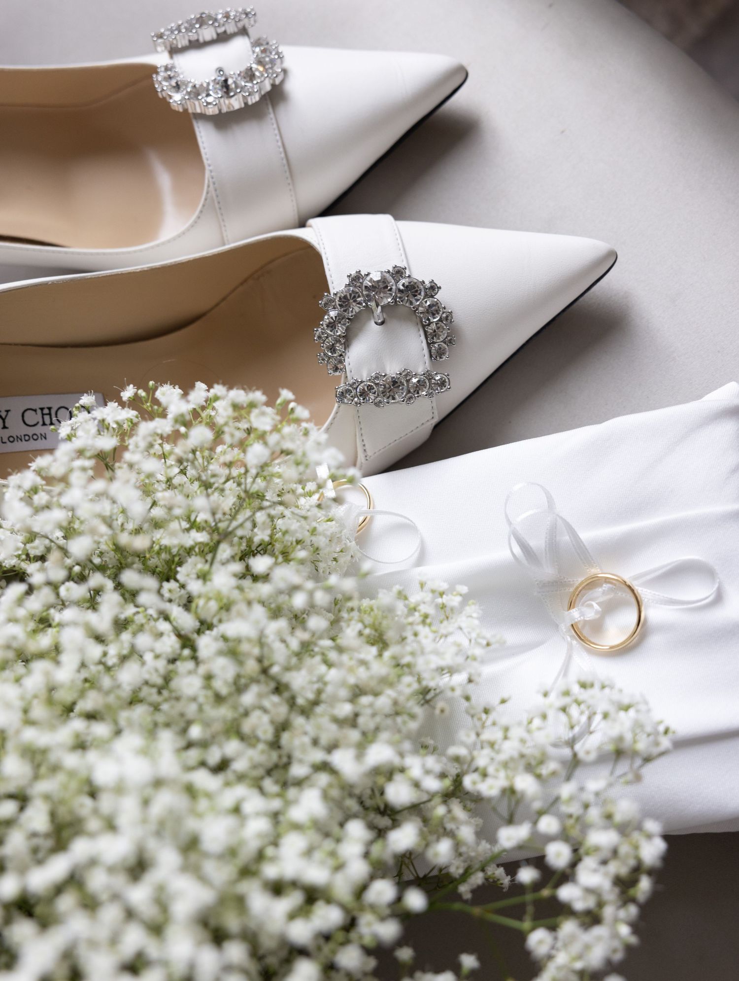 Wedding accessories including white heels, crystal buckles, rings and baby's breath flowers.
