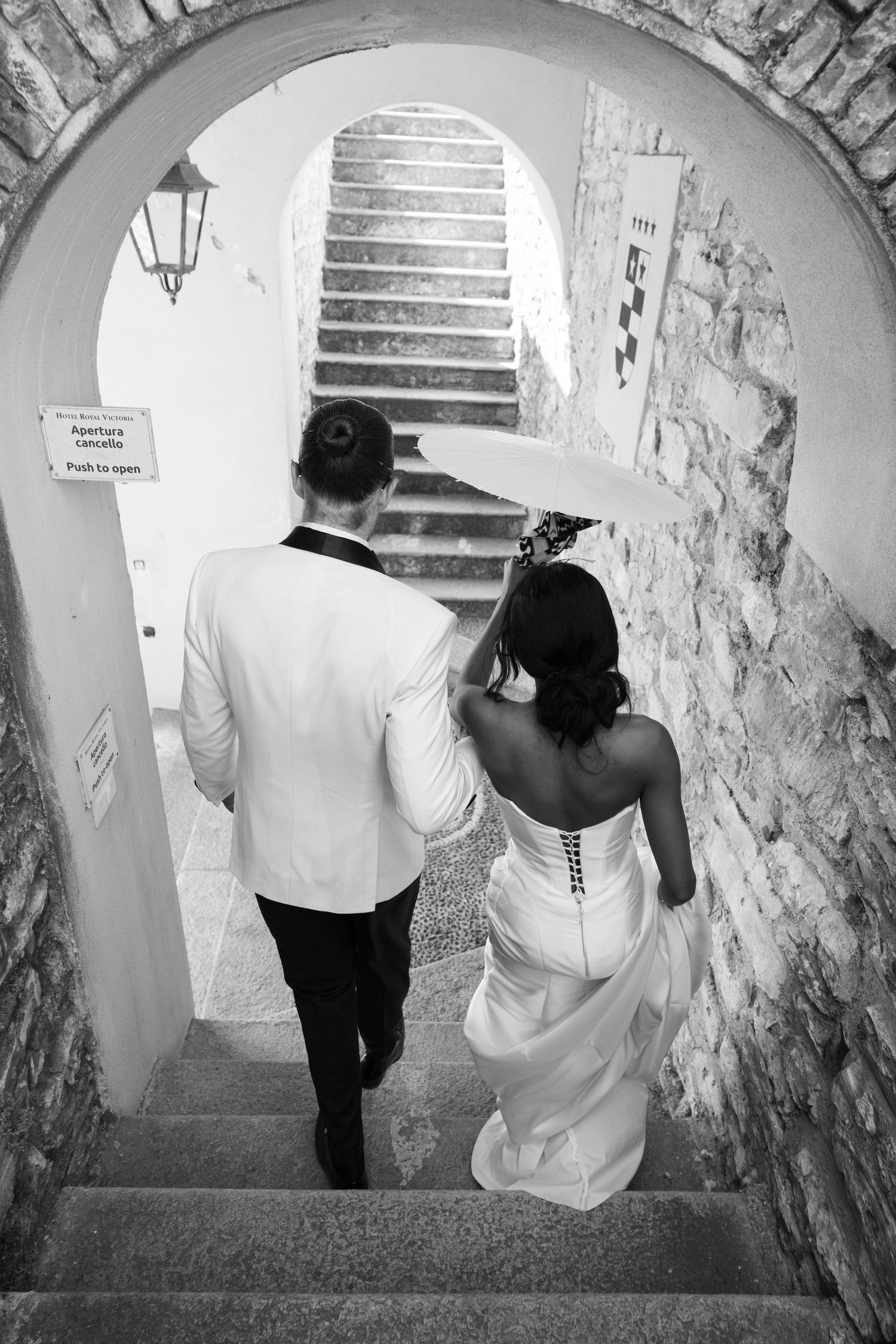 A series of black and white photos showing a couple descending stone stairs in a rustic arched passageway.