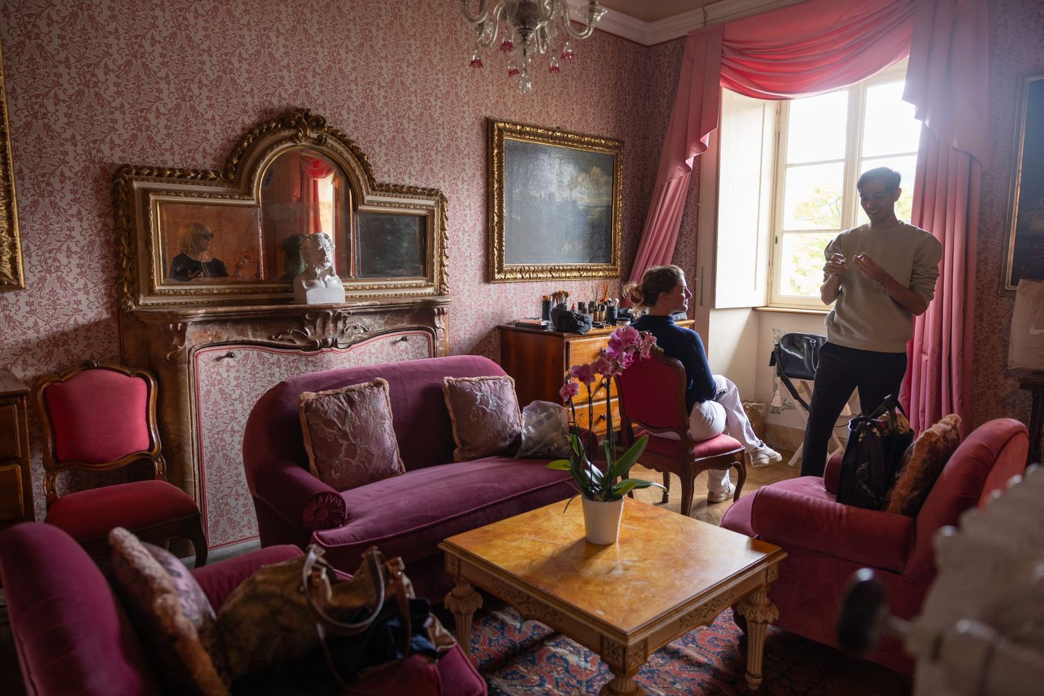 Elegant Victorian-style room with ornate furniture, red drapes, and vintage decor.