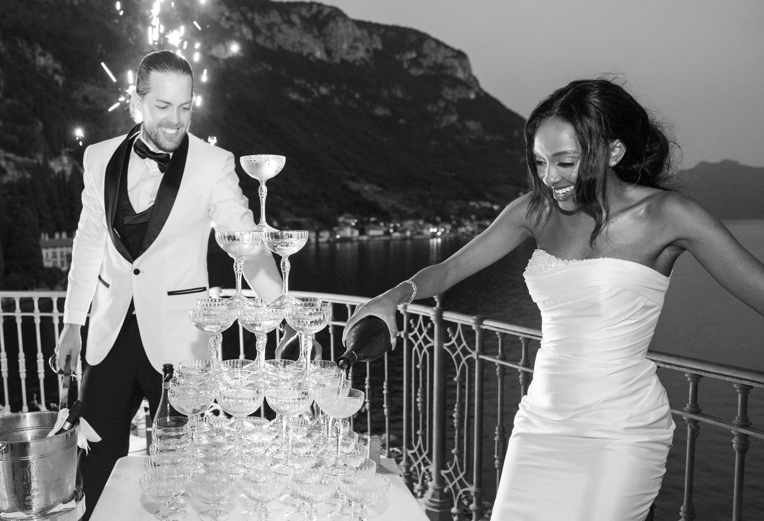 A series of black and white photos showing people in white dresses celebrating on a scenic balcony overlooking mountains.