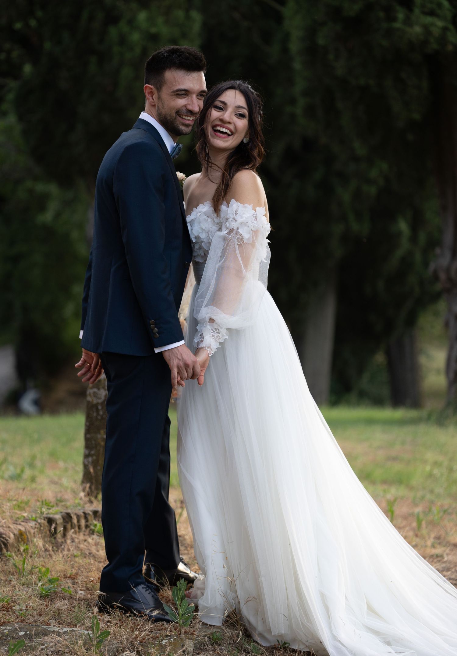 Joyful wedding moment captured in a natural outdoor setting with trees in background.