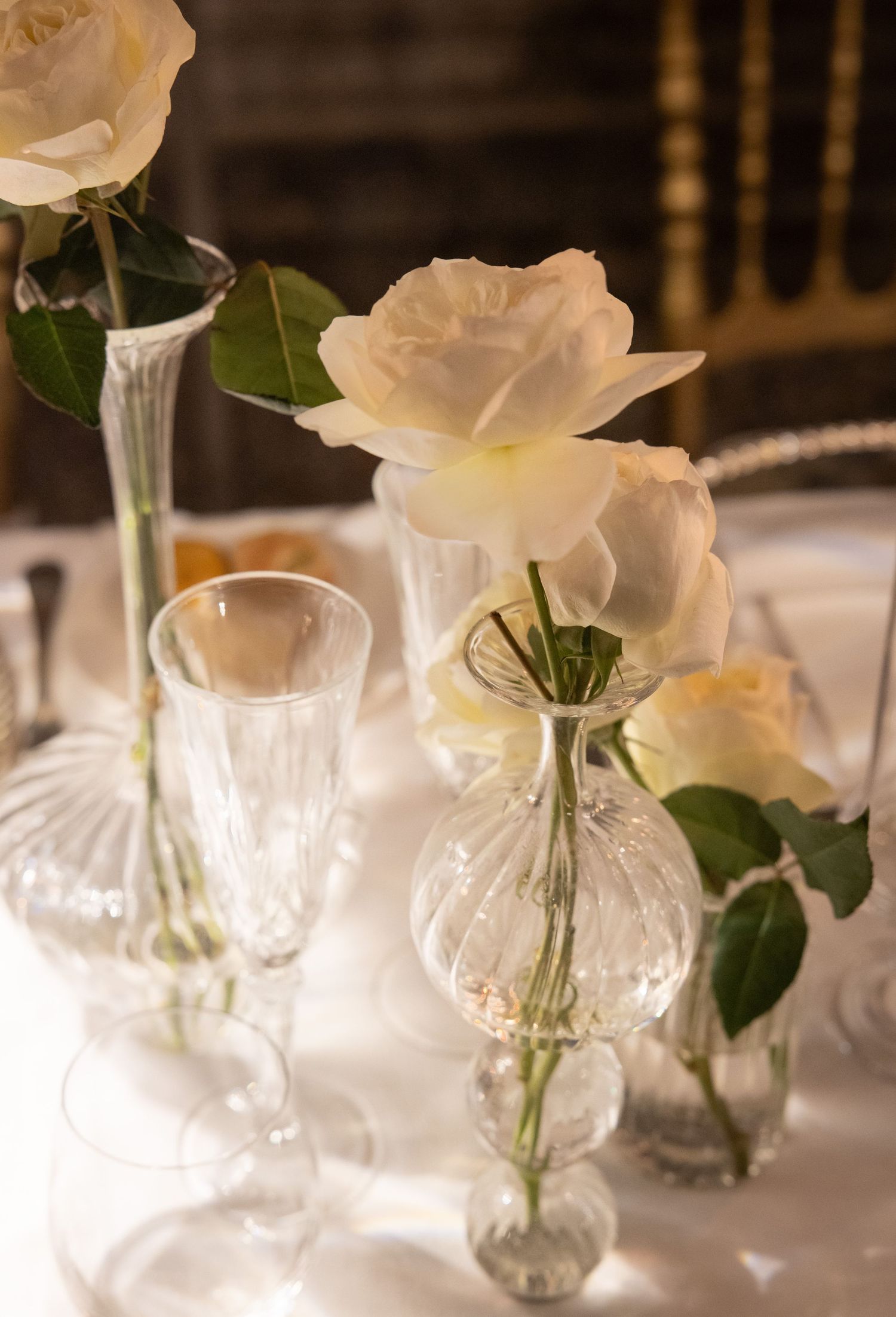 White roses in delicate glass vases arranged on elegant dining tables.