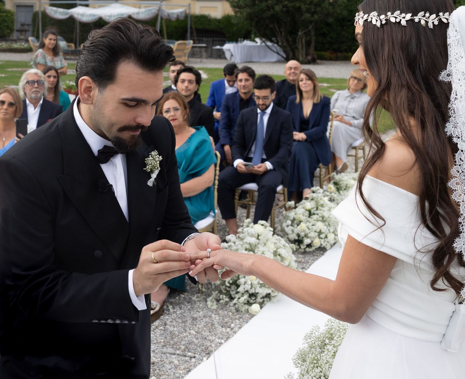 Elegant wedding celebration with guests throwing confetti in an outdoor garden setting.