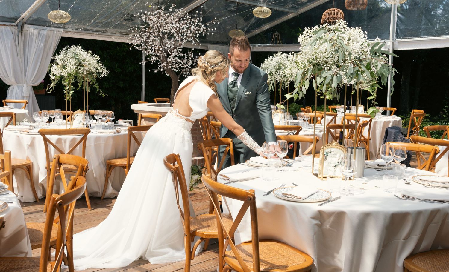 Elegant wedding reception setup with wooden chairs and white floral centerpieces.