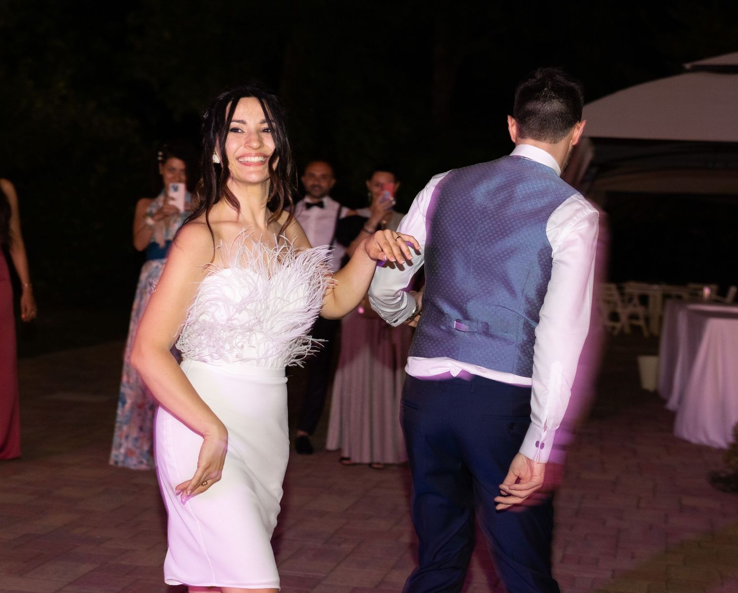 Wedding party dancing during an evening reception on an outdoor dance floor.